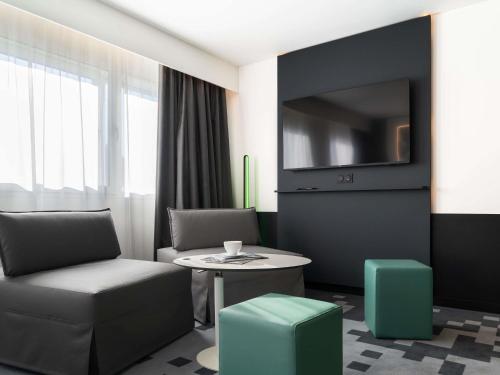 a room with a chair and a table and a tv at Mercure Béziers in Béziers
