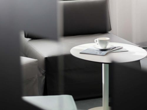 a small white table with a cup on it next to a chair at Mercure Béziers in Béziers