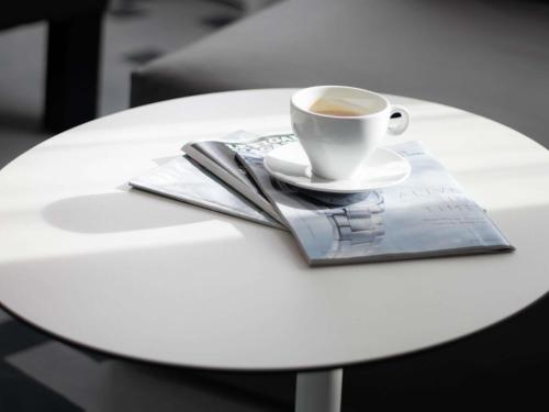 a cup of coffee sitting on a table with a newspaper at Mercure Béziers in Béziers