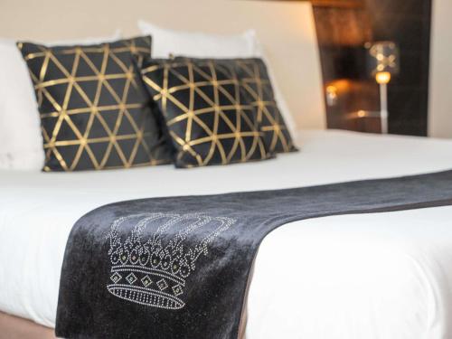 a bed with black and white sheets and pillows at Mercure Le Mans Centre in Le Mans