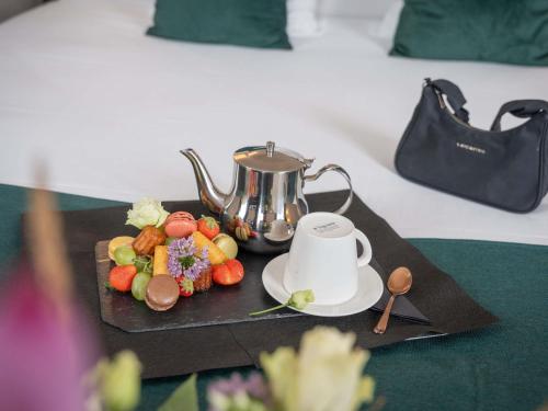 a tray with a tea pot and a plate of fruit at Mercure Le Mans Centre in Le Mans