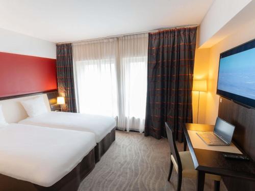 a hotel room with a bed and a desk with a laptop at Mercure Le Mans Centre in Le Mans
