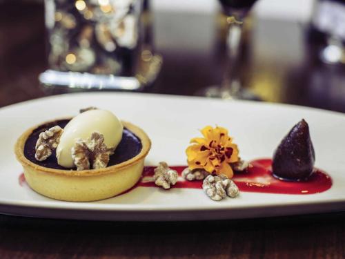 a white plate with a dessert on a table at Mercure Le Mans Centre in Le Mans