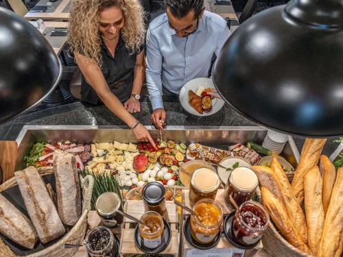 a group of people standing around a buffet of food at Mercure Le Mans Centre in Le Mans