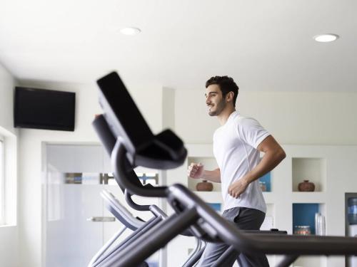 a man running on a treadmill in a gym at Mercure Le Mans Centre in Le Mans