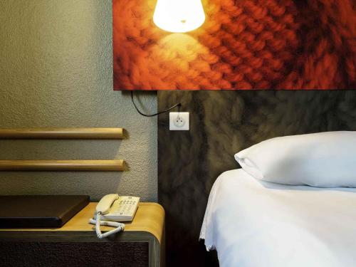 a hotel room with a bed and a phone on a table at ibis Honfleur in Honfleur