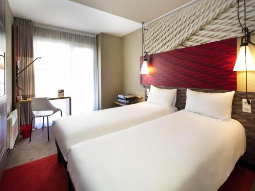 a hotel room with two beds and a desk at ibis Honfleur in Honfleur