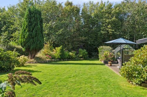 a garden with a green lawn and a blue umbrella at Holiday Paradise With Pool Near Havnsø Beach in Føllenslev
