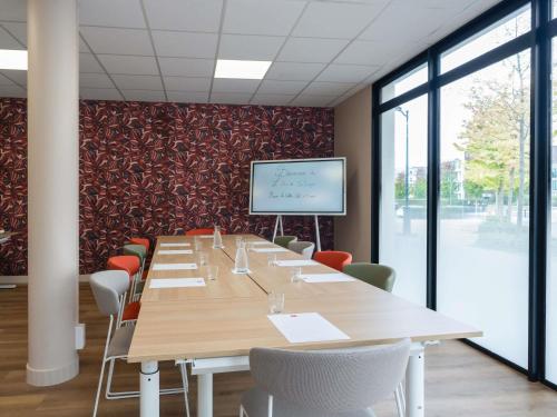a large conference room with a long table and a screen at ibis Marne La Vallée Val d'Europe in Montévrain