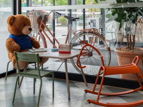 a teddy bear sitting in a chair next to a table at ibis Marne La Vallée Val d'Europe in Montévrain