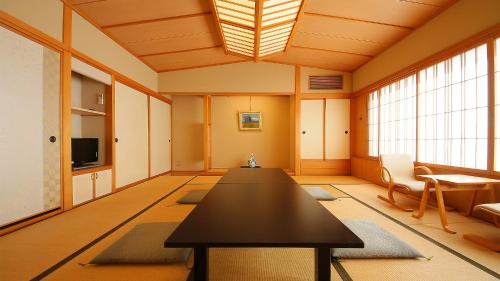 a large room with a table and chairs and windows at Hotel Symphony Annex Sagae Onsen in Sagae