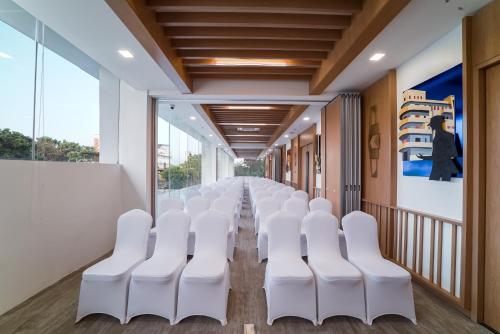 a conference room with white chairs and a corridor at Truntum Cihampelas in Bandung