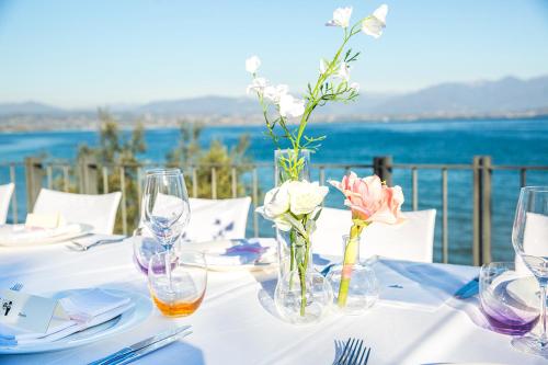 a table with a white table cloth with flowers in vases at Hotel Acquaviva Del Garda in Desenzano del Garda