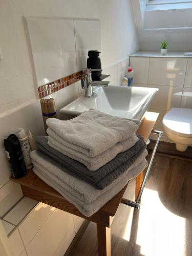 a bathroom with a sink and a pile of towels at Süße kleine Ferienwohnung in Pirna