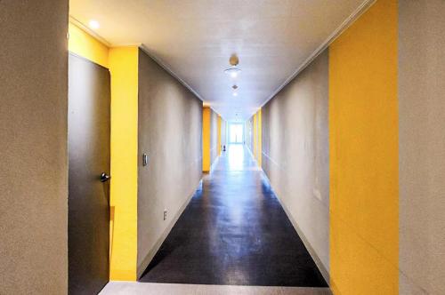 an empty hallway with yellow walls and a long corridor at Whinstone Hotel & Resort in Jeju