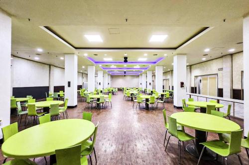 a cafeteria with green tables and chairs in it at Whinstone Hotel & Resort in Jeju