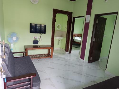 a living room with a couch and a tv on the wall at Sili Homestay in Madikeri