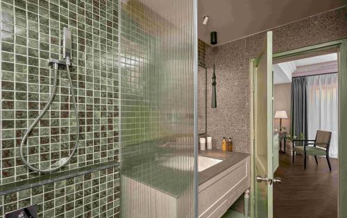 a bathroom with a sink and a shower with green tiles at President Maison Signature By M Village in Ho Chi Minh City