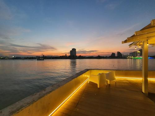 a dock with two white chairs on the water at night at Chao phraya riverfront house Baan Rimphraya in Bangkok