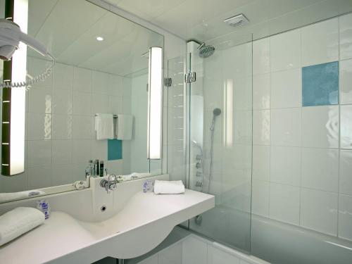 a bathroom with a shower and a sink and a mirror at Novotel Le Havre Centre Gare in Le Havre