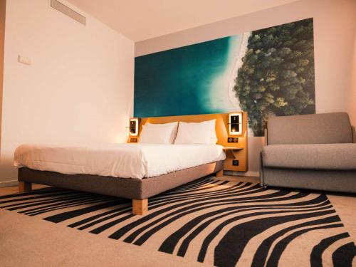 a bedroom with a bed and a chair at Novotel Le Havre Centre Gare in Le Havre