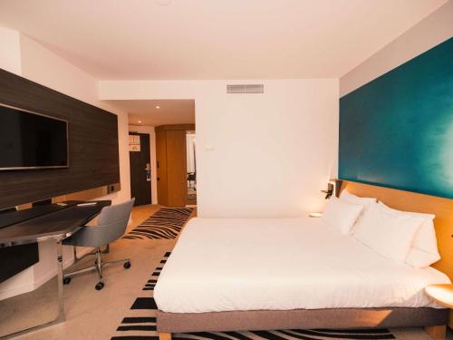 a hotel room with a bed and a desk at Novotel Le Havre Centre Gare in Le Havre
