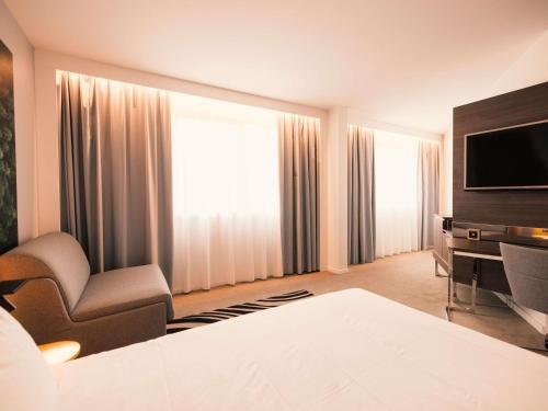 a hotel room with a television and a chair at Novotel Le Havre Centre Gare in Le Havre