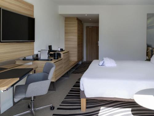 a hotel room with a bed and a flat screen tv at Novotel Le Havre Centre Gare in Le Havre