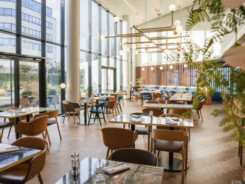 a restaurant with tables and chairs and windows at Novotel Le Havre Centre Gare in Le Havre