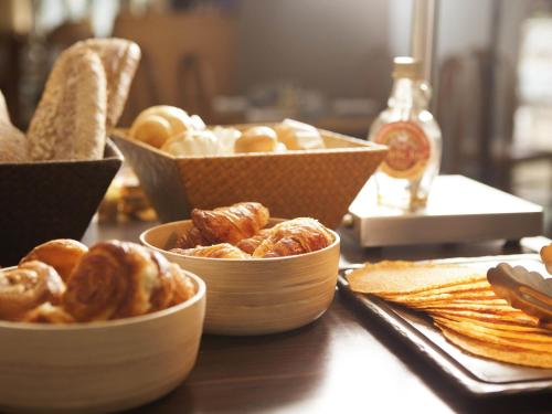 a table topped with bowls of bread and pastries at Novotel Le Havre Centre Gare in Le Havre