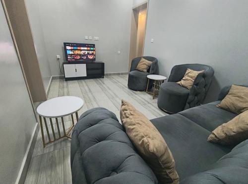 un salon avec un canapé, des chaises et une télévision dans l'établissement Kigali Mechatronics Place, à Kigali