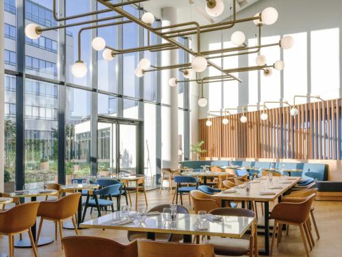 a restaurant with tables and chairs and large windows at Novotel Le Havre Centre Gare in Le Havre
