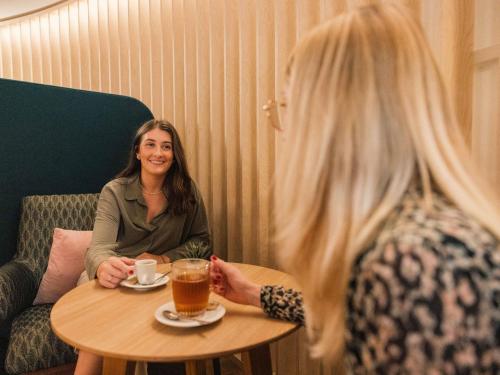 a woman sitting at a table with a cup of coffee at Novotel Le Havre Centre Gare in Le Havre