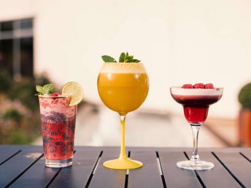 three cocktails sitting on a wooden table at Novotel Le Havre Centre Gare in Le Havre