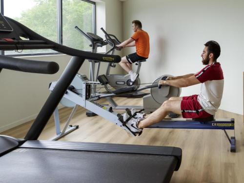 two men on a treadmill in a gym at Novotel Le Havre Centre Gare in Le Havre