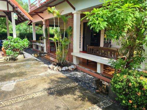 a porch of a house with a bench and trees at Sawaddee Holland in Ban Phlong Takhe