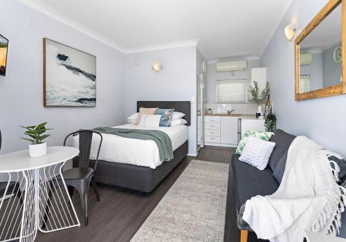 a bedroom with a bed and a table and a chair at Bombo Breeze in Kiama