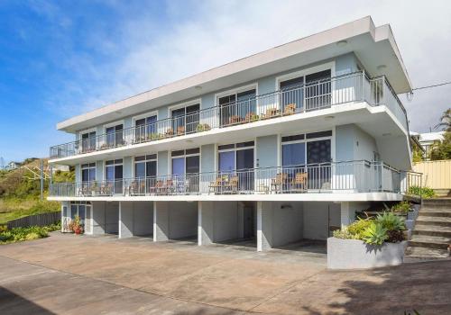 a large white building with balconies and chairs at Bombo Breeze in Kiama