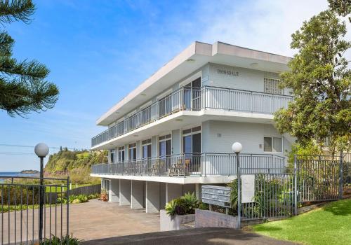 a white building with balconies and a fence at Bombo Breeze in Kiama