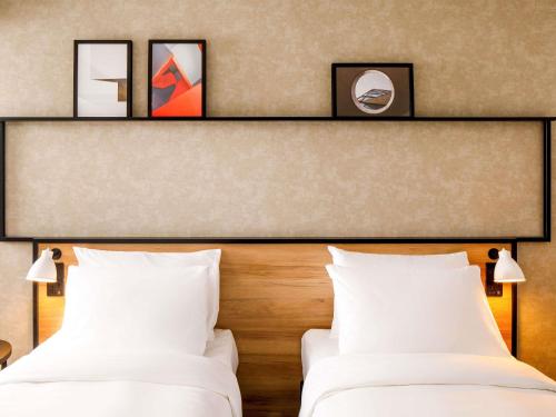 two beds in a hotel room with white pillows at ibis Porto Alegre Aeroporto in Porto Alegre