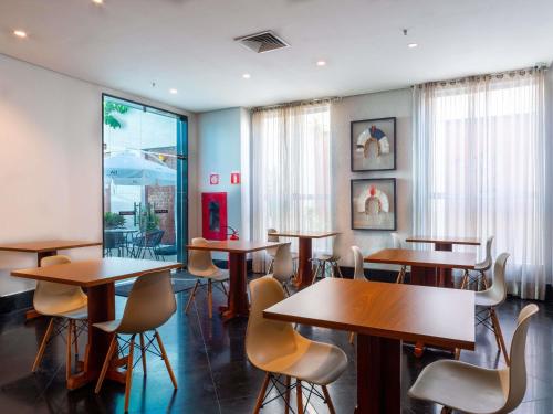 a restaurant with wooden tables and chairs and windows at Mercure Manaus in Manaus