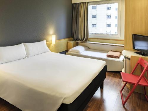 a hotel room with a bed and a desk and a window at ibis Santo Andre in Santo André