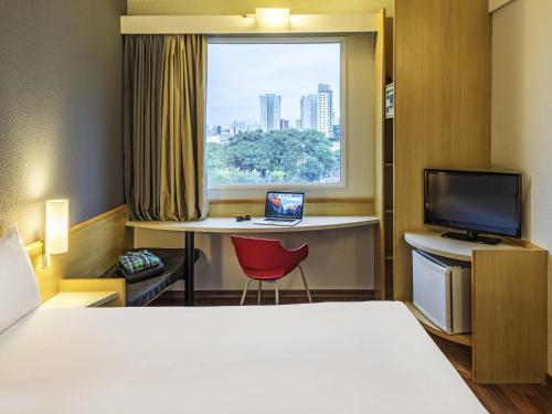 a hotel room with a bed and a desk and a window at ibis Santo Andre in Santo André
