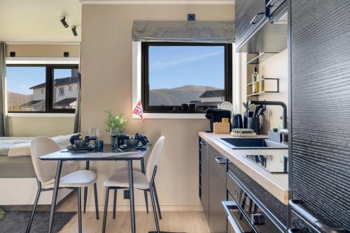a small kitchen with a table and chairs and a window at Premium Studio by Arctic Seasons - A Cozy Luxury Escape at the Top of Tromsø in Tromsø
