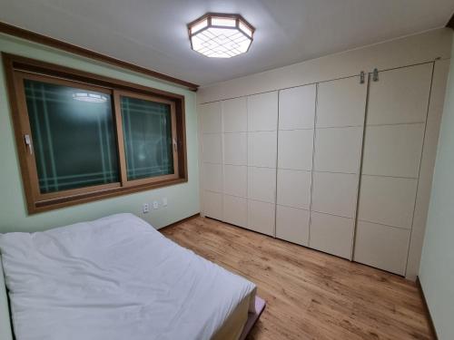 an empty room with a bed and a window at 꽃이피다 in Kulchŏn