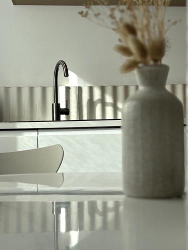 a vase with flowers sitting on a counter next to a sink at La baraque Calais in Sangatte