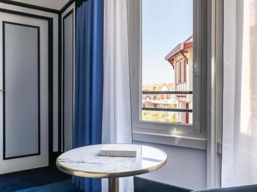 a table sitting in front of a window with a view at Hotel Plaza Biarritz Plage - Handwritten Collection in Biarritz