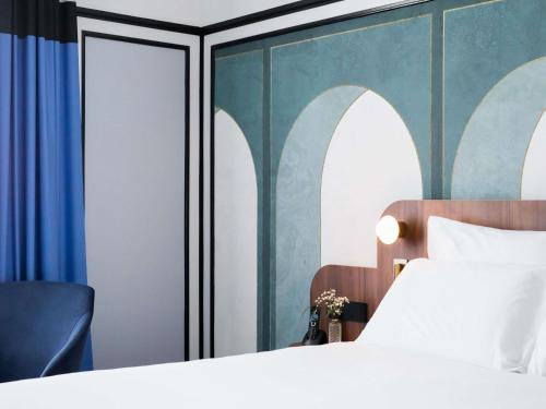 a bedroom with a bed and a blue wall at Hotel Plaza Biarritz Plage - Handwritten Collection in Biarritz