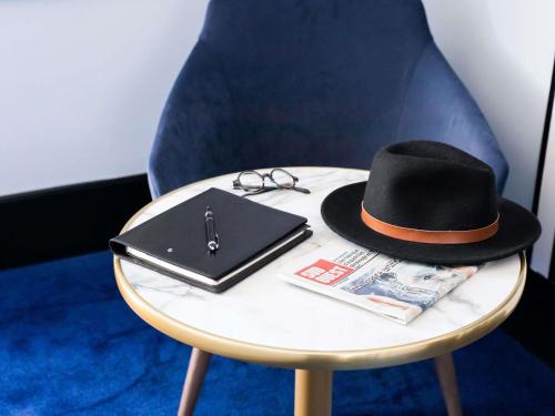 a black hat and glasses on a table at Hotel Plaza Biarritz Plage - Handwritten Collection in Biarritz