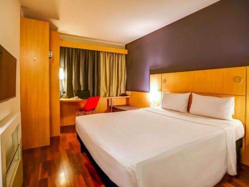 a hotel room with a large white bed and a desk at ibis Rio de Janeiro Santos Dumont in Rio de Janeiro